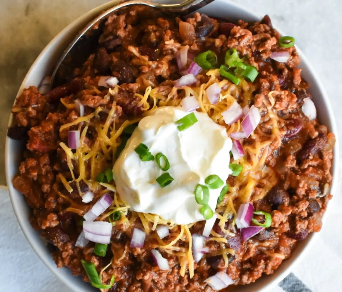 Bowl of authentic Texas red chili with toppings